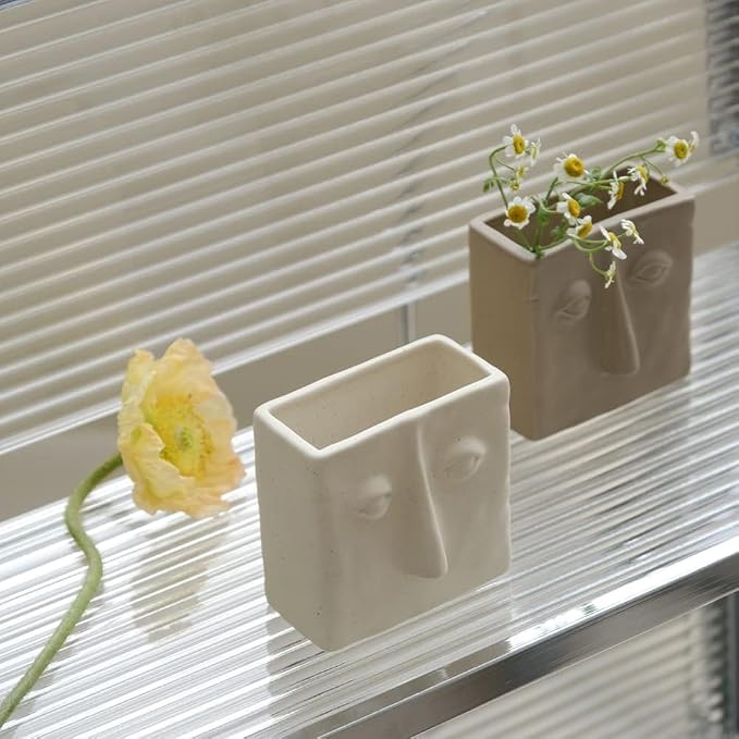 WENSHUO Ceramic Pen Holder, Pencil Holder for Desk, Desk Accessories, Crème | 3.7 in tall ceramic holder for pens, pencils, makeup brushes, or toothbrushes. Abstract face design displays small plants.